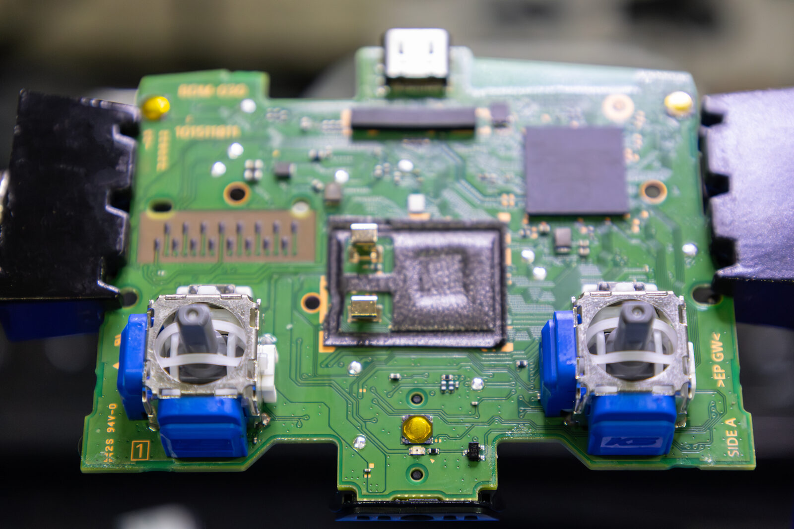 A PS5 DualSense circuit board with BDM-030 printed on the silkscreen, fitted with replacement blue joystick modules