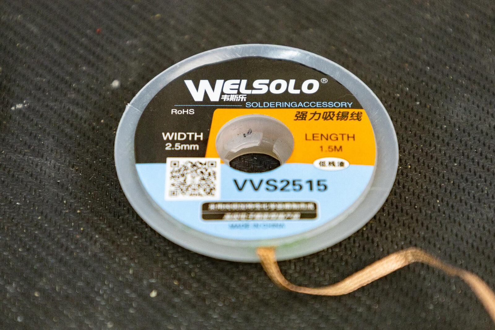 A reel of Welsolo VVS2515 solder braid, 2.5mm wide, with a length of copper braid unspooled